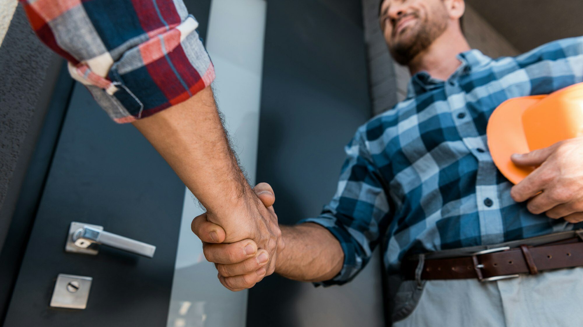 cropped view of men shaking hands while standing near door